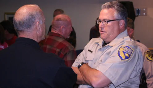 Photo by Steve GOLDSWORTHY Andrew Hughan of the Dept. of Fish and Wildlife (right) talks to a resident after the wildlife forum on Tuesday night.