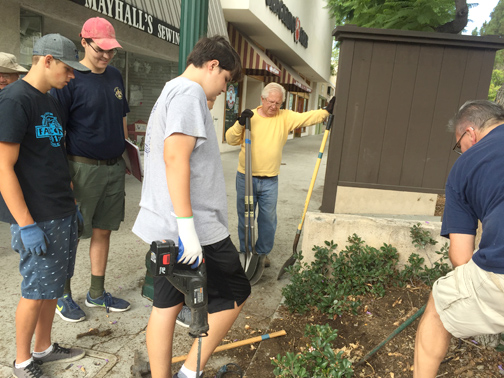 Januzik with his volunteers get direction on removing an old plaque from the grounds of the Montrose Shopping Park. 